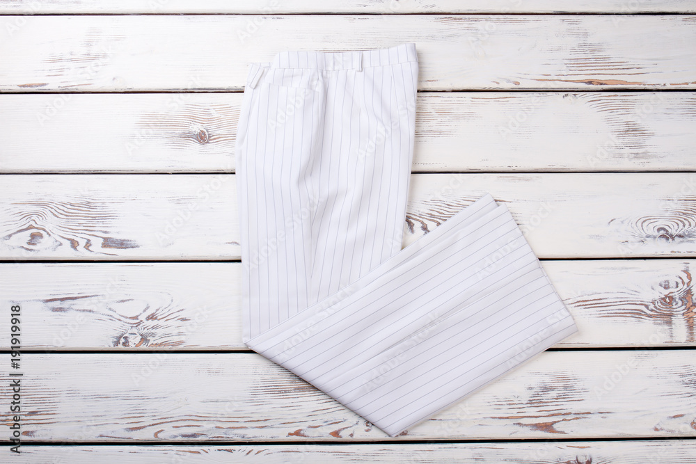 Female white business style trousers. Women classic clothes on wooden background. Feminine brand apparel on sale.