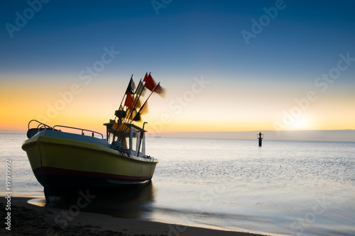 The rising sun illuminates the fishing boat. Baltic sea.