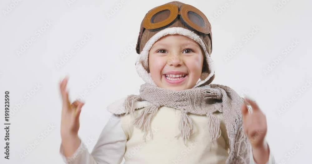Portrait of a girl, dressed as a pilot or aviator with a hat and glasses, smiles looking at the camera as she dreams with open eyes and thinks about the future. Concept of: success, future, dreams Portrait of a girl, dressed as a pilot or aviator with a hat and glasses, smiles looking at the camera as she dreams with open eyes and thinks about the future. Concept of: success, future, dreams