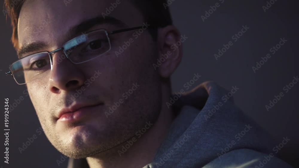 Young unshaved caucasian man in glasses sitting in front of computer at night start smiling getting an breakthrough, close up portrait Young unshaved caucasian man in glasses sitting in front of computer at night start smiling getting an breakthrough, close up portrait