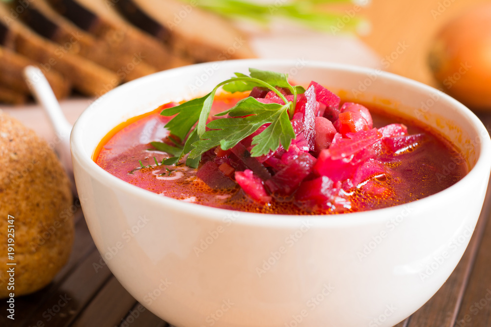 Borscht-vegetable beetroot soup, on the table with slices of rye cereal bread and gluten of sour cream, garlic and herbs. Rustic style. Borscht-vegetable beetroot soup, on the table with slices of rye cereal bread and gluten of sour cream, garlic and herbs. Rustic style.