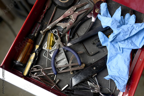 overhead view of toolbox full of tools and work gloves inside a workshop. 