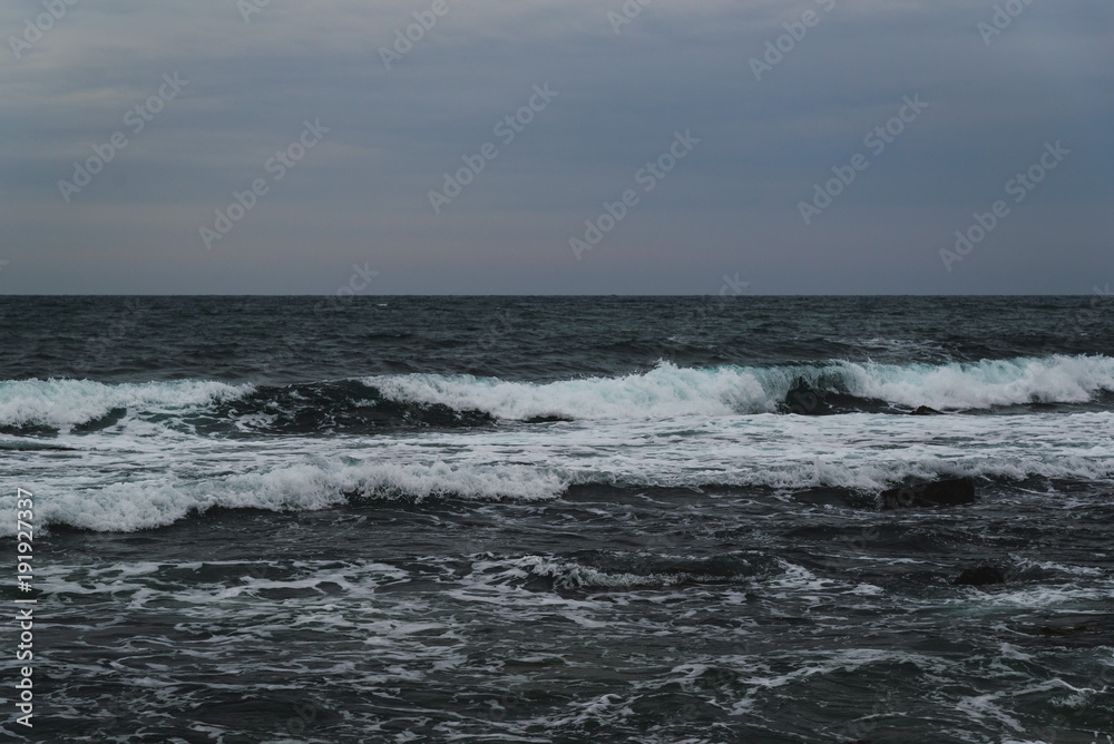 Storm on the sea in cloudy weather at sunset