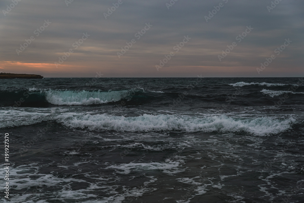 Storm on the sea in cloudy weather at sunset