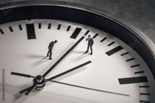 Two businessman standing in the middle of clock face. Business concept