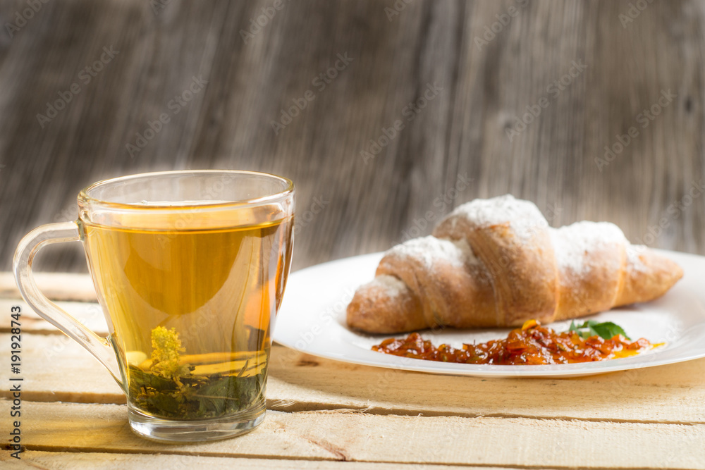 Breakfast with herbal tea and croissant on wooden vintage table