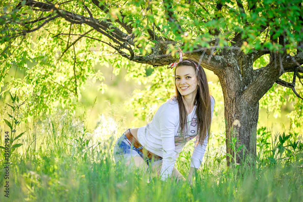beautiful young girl is sitting on the grass in the garden beautiful young girl is sitting on the grass in the garden