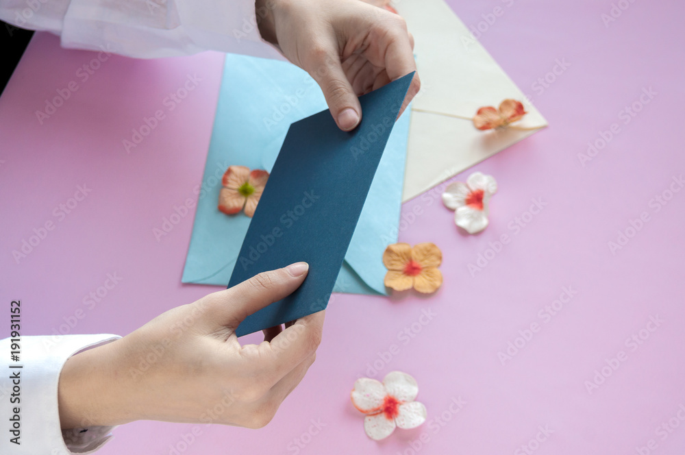 Female hands holding a blue envelope on a pink background