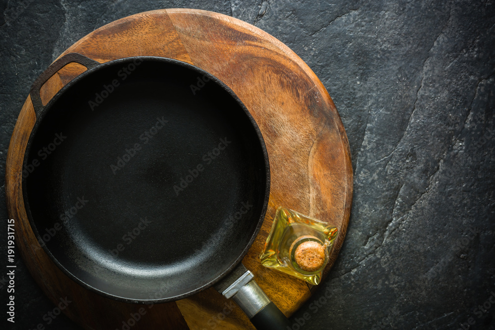 A black cast-iron frying pan for cooking food. Vegetable oil with spices.