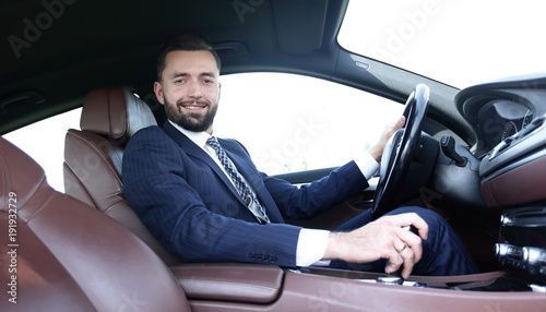 View from the side confident businessman sits at the wheel of a car © ASDF