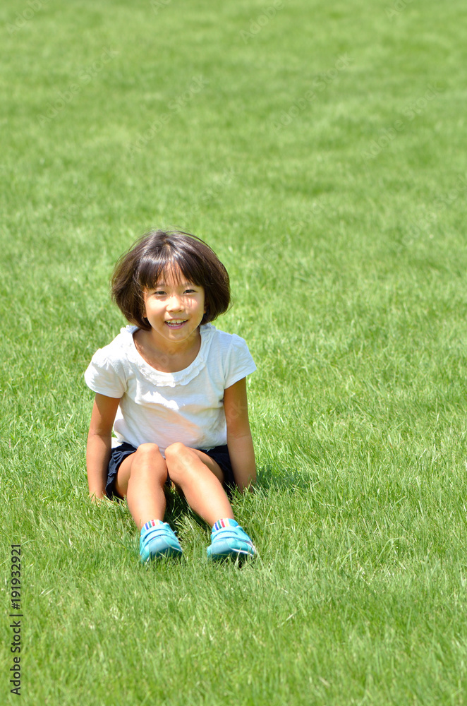 芝生広場で座る笑顔の女の子 芝生広場で座る笑顔の女の子
