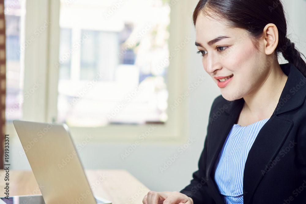 Smiling business woman in black suit is sitting working on laptop in office. Happy work concept. Smiling business woman in black suit is sitting working on laptop in office. Happy work concept.