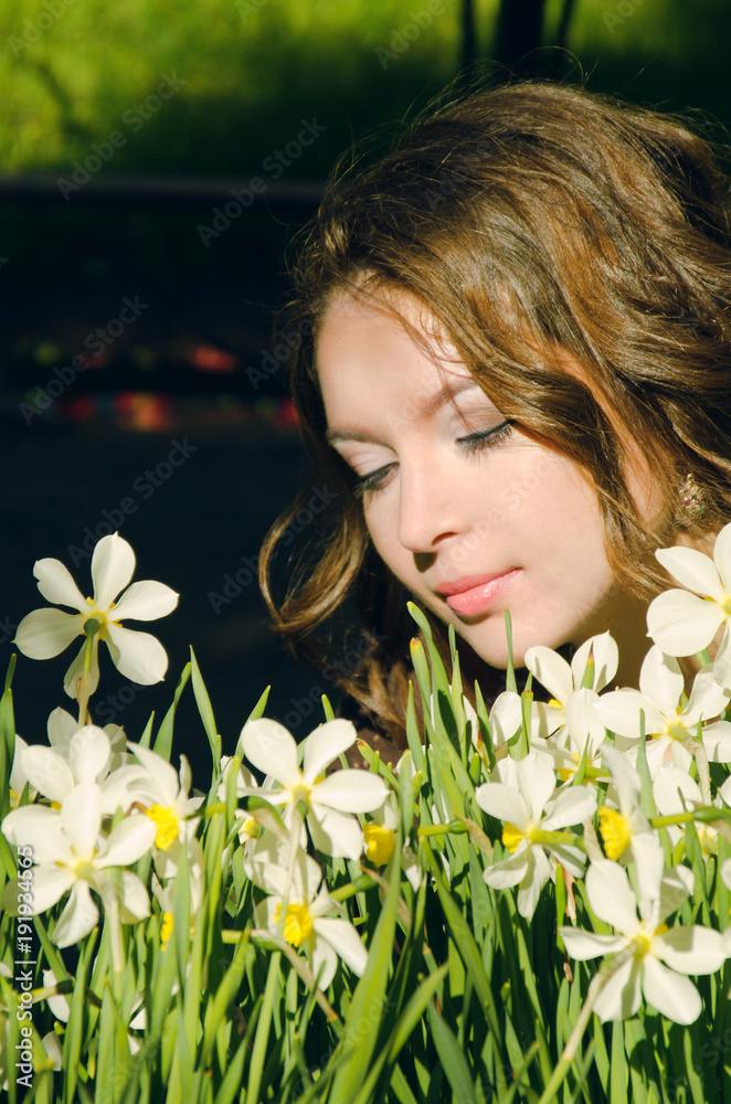 Naklejka premium woman in boho style dress sat down to relax near the flowerbed with daffodils in the Park