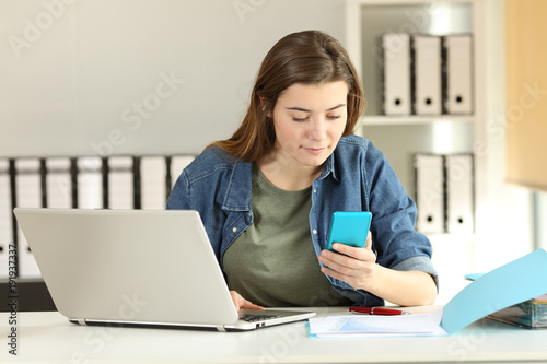 Intern checking phone message at office