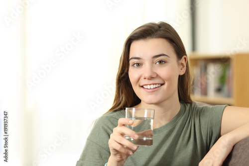 Happy teen holding a glass of water looking at you