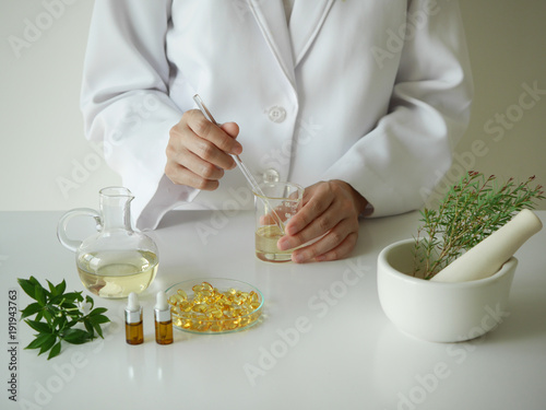 scientist or doctor making herbal medicine with herb leaves , capsule, tablets. hands.