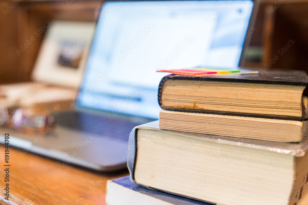 Fototapeta premium Working classic wooden desk with books and soft background of laptop