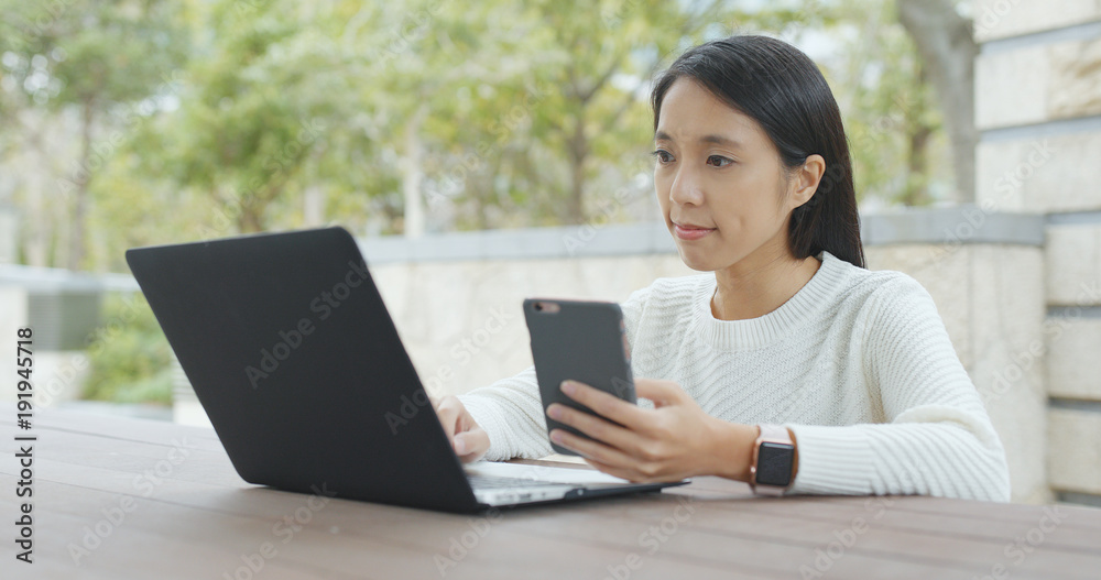 Woman using laptop computer and cellphone at outdoor coffee shop Woman using laptop computer and cellphone at outdoor coffee shop