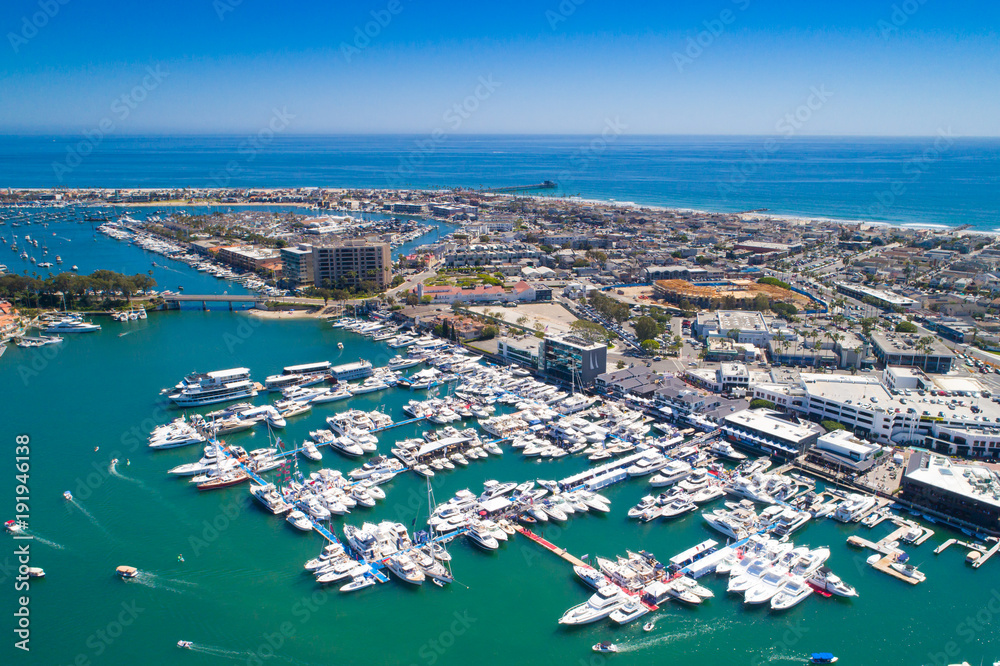 Cinematic aerial view over the Newport Beach harbor during the annual boat show with luxury yachts, boats and Duffy boats on a sunny blue sky day.