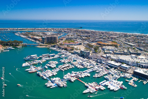 Cinematic aerial view over the Newport Beach harbor during the annual boat show with luxury yachts, boats and Duffy boats on a sunny blue sky day.
