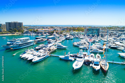 Cinematic aerial view over the Newport Beach harbor during the annual boat show with luxury yachts, boats and Duffy boats on a sunny blue sky day.