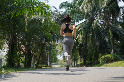 Young fitness sports woman runner running on tropical park trail