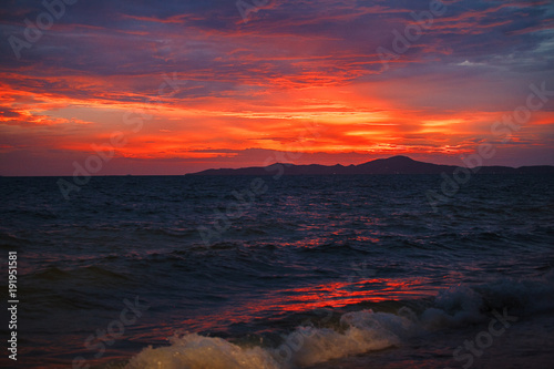 red sunset on the beach. Beach with waves at dusk. © Ilshat