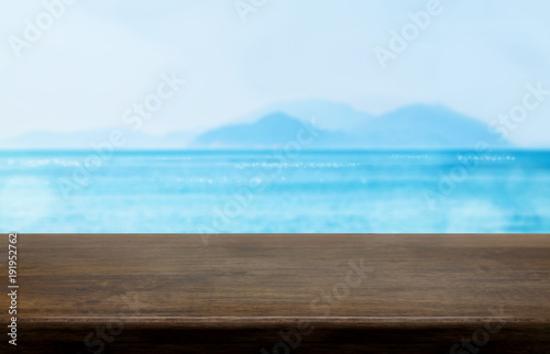 Empty old dark wood table top with blur blue sky and sea bokeh background Mock up template for display or montage of product or content use as banner in social media ads