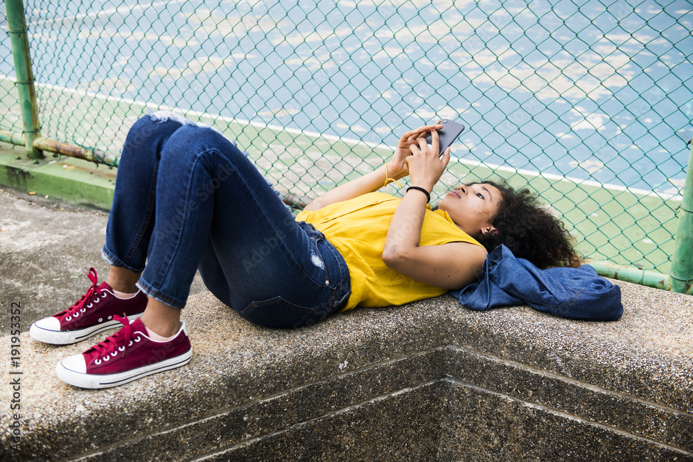 Young woman lying down in the park using a smartphone Young woman lying down in the park using a smartphone