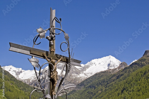 Schmiedeisernes Kreuz mit schneebedecktem Berg