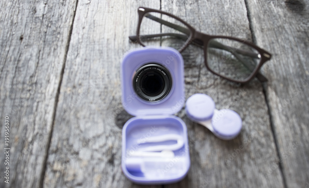 Contact lenses, tweezers on in pack on wooden background Contact lenses, tweezers on in pack on wooden background