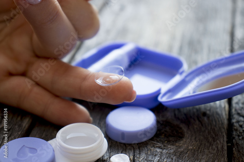 contact lens on finger on wooden background, hand was holding soflens photo