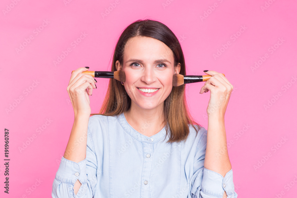Professional makeup artist with brushes on pink background Professional makeup artist with brushes on pink background