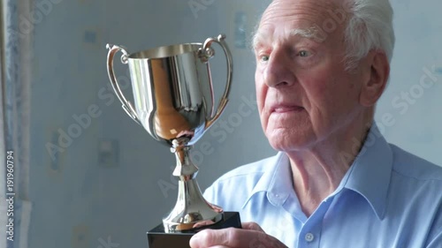 Elderly man inspecting his trophy in his living room