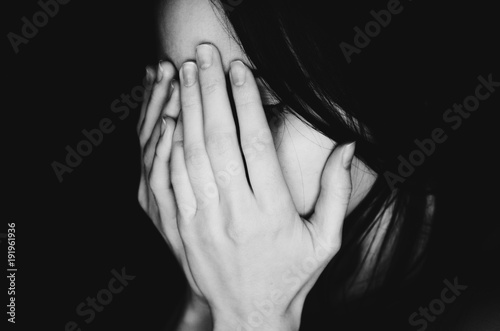 Crying young girl covers her face with hands black white