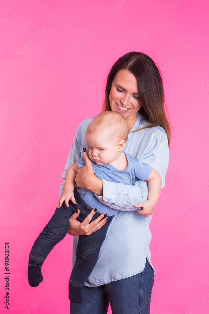 happy young mother with a baby child on pink background happy young mother with a baby child on pink background