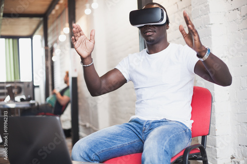Young man wearing virtual reality glasses in modern interior design coworking studio. Smartphone using with VR goggles headset
