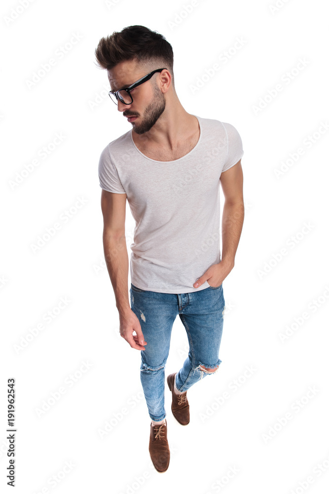 young man looks away while standing with hand in pocket young man looks away while standing with hand in pocket