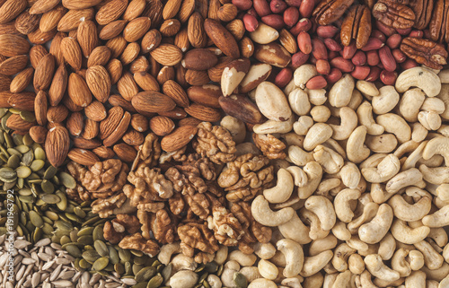 A variety of nuts and seeds background, food background, vegan healthy food concept. Copy space, top view.