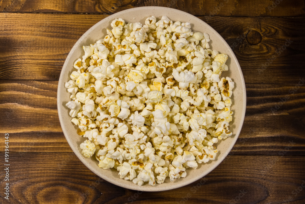 Bowl with popcorn on wooden table Bowl with popcorn on wooden table