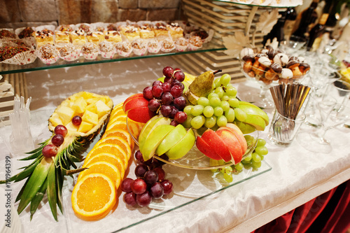 Close-up photo of a huge variety of fruits and sweet desserts on the wedding banquet.