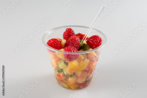 a fruit salad in take away clear plastic cup on white background