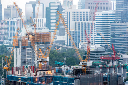 Side high-rise tower crane with a multi-storey building under construction against