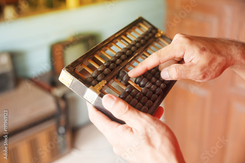 Man hands accounting with old Chinese abacus.