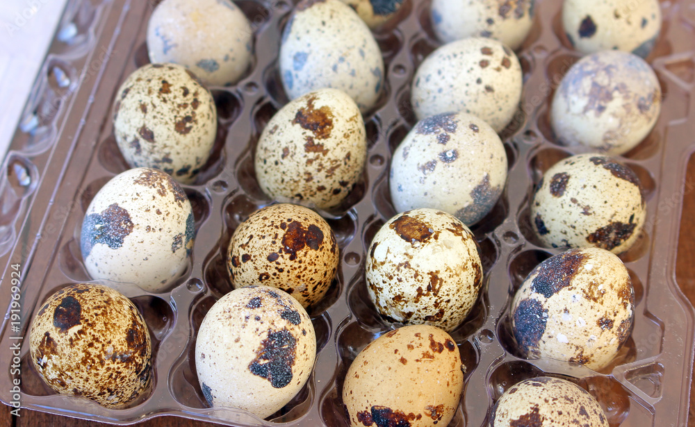 Quail eggs in a transparent plastic container on a wooden kitchen table Quail eggs in a transparent plastic container on a wooden kitchen table