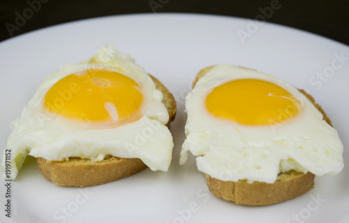 Two sandwiches with egg on a white plate.
