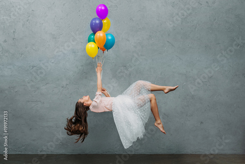 Canvastavla young woman levitating with colorful balloons