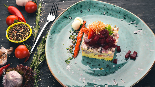 Russian traditional cuisine. Shub salad with herring. Top view. On a black wooden background. Copy space. photo