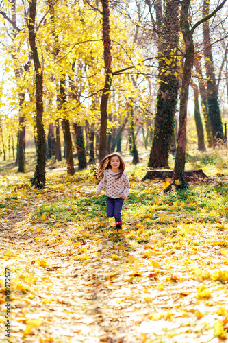 Portrait of little girl running in autumn park.