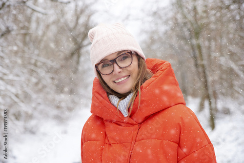Woman walking outdoor in winter. Close-up portrait shot a happy woman wearing hat and warm coat while standing outdoor and enjoy snowy weather.  © sepy